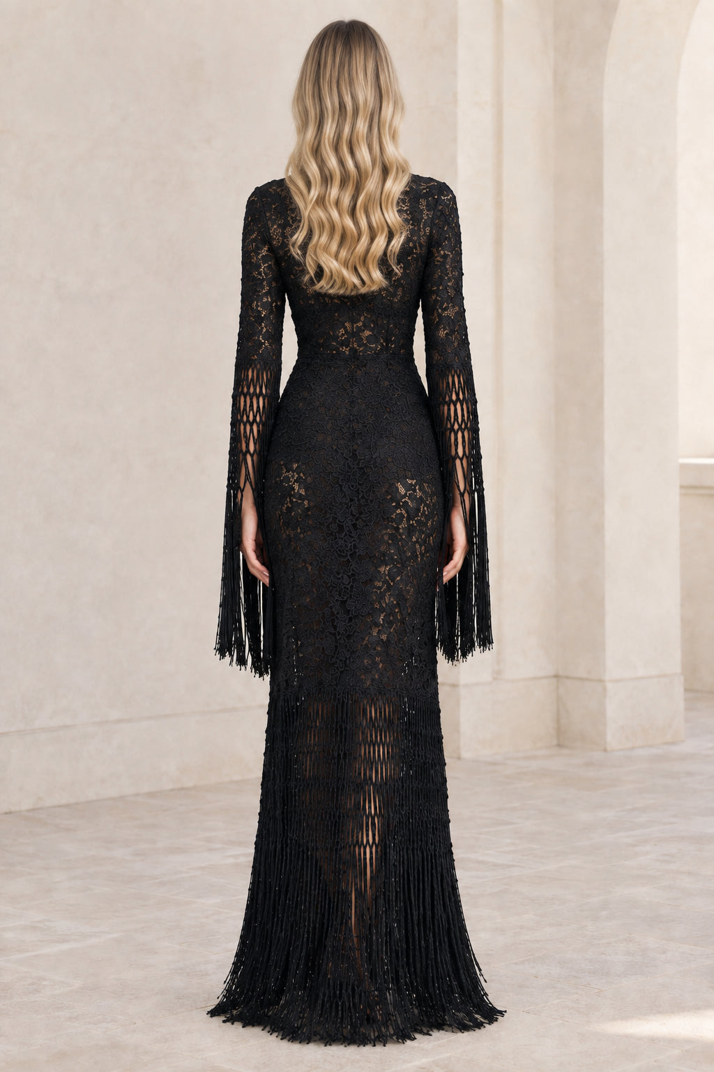 Back view of model wearing black lace evening dress with fringe details
