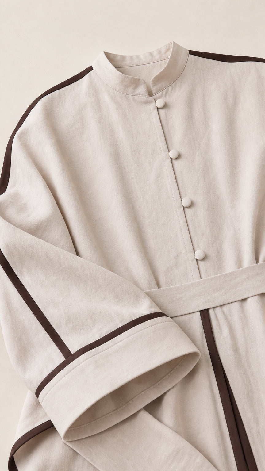 Close-up detail of mandarin collar, covered buttons, and contrast piping on beige fabric