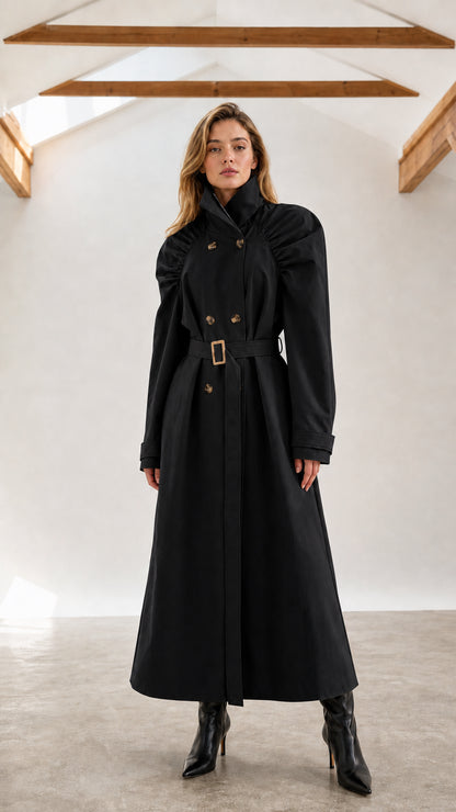 Front full-length view of woman wearing black ruched shoulder maxi trench coat