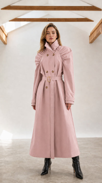 Front full-length view of woman wearing dusty pink ruched shoulder maxi trench coat