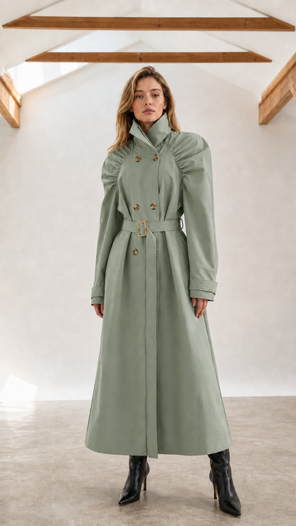 Front full-length view of woman wearing sage green ruched shoulder maxi trench coat