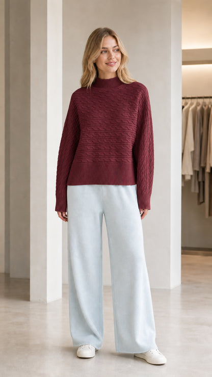 Model wearing burgundy wine red mock neck cable knit sweater with light blue pants
