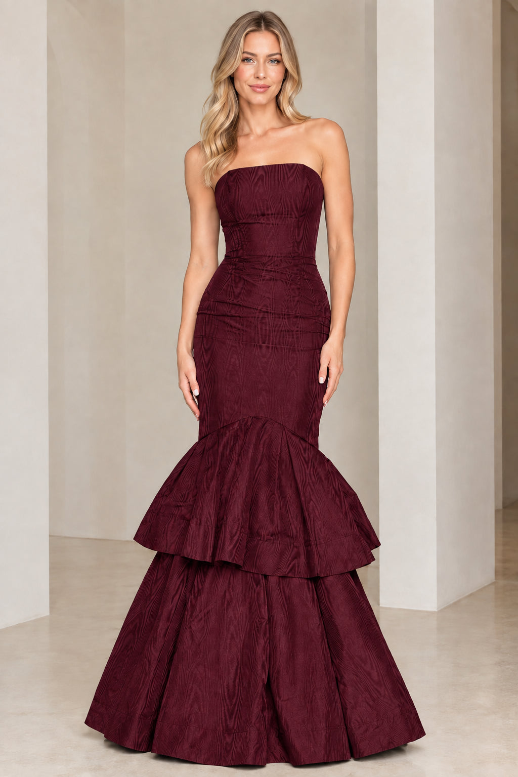 Model wearing burgundy wine strapless tiered mermaid evening gown