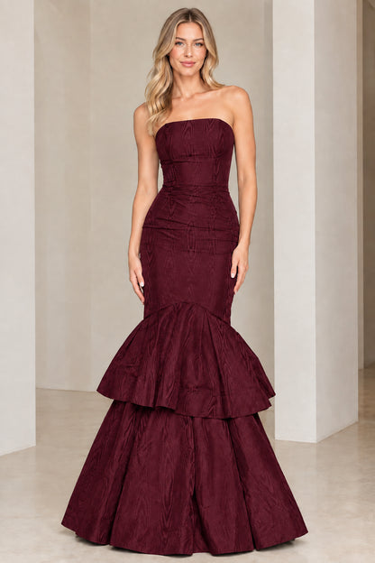 Model wearing burgundy wine strapless tiered mermaid evening gown