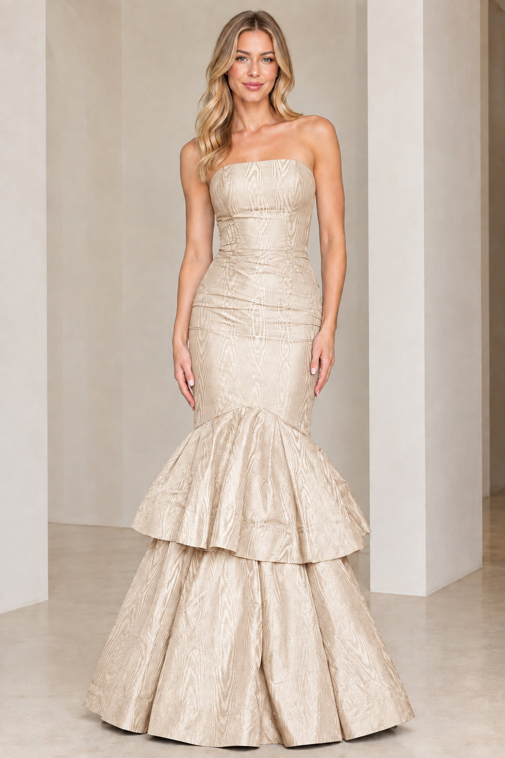 Model wearing champagne gold strapless tiered mermaid evening gown